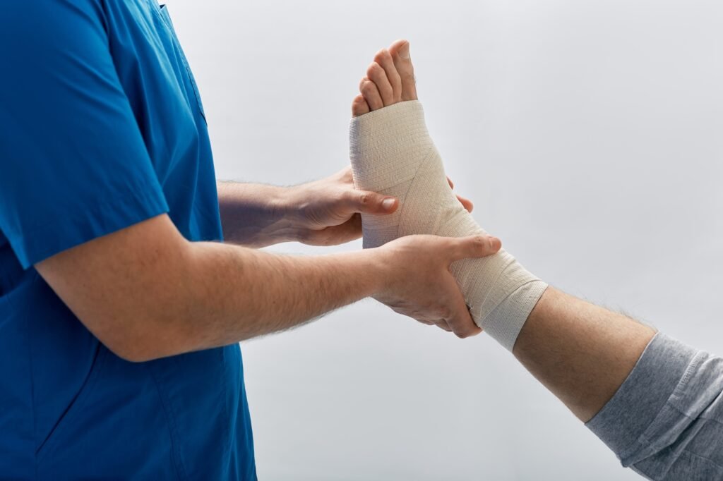Doctor wrapping male patient's foot with elastic bandage for treat muscle sprains in doctor's