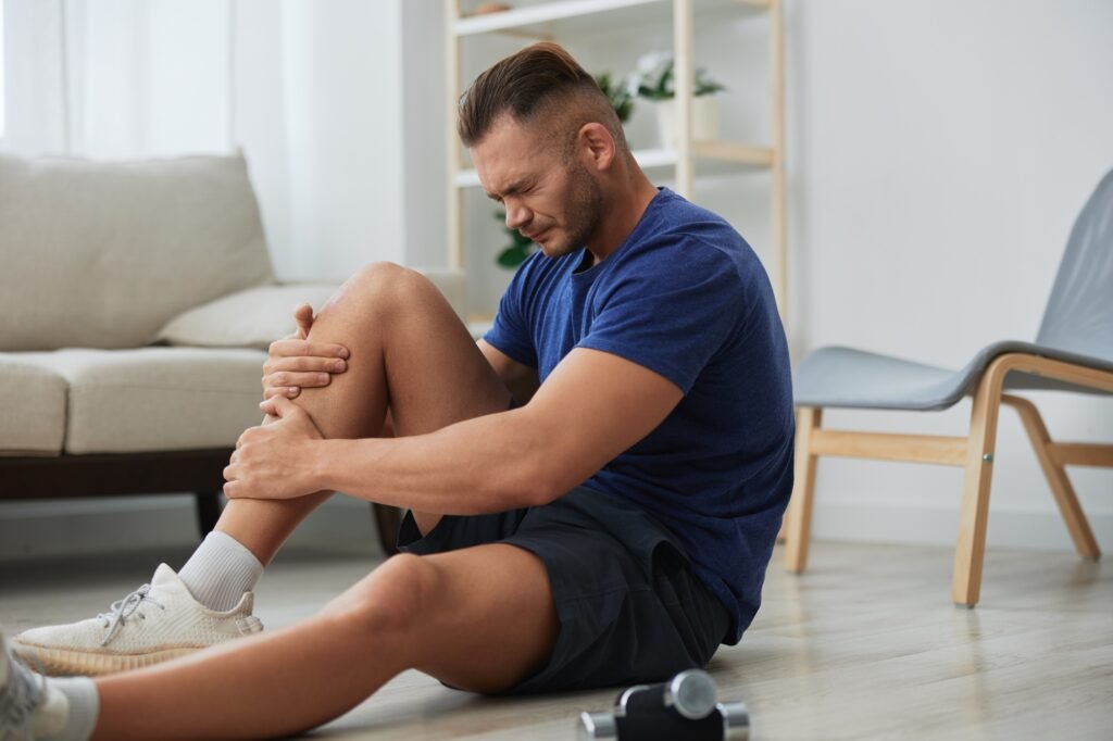 Man athlete pain and injury back arm and leg at home, sports injury bodybuilder, concept health and